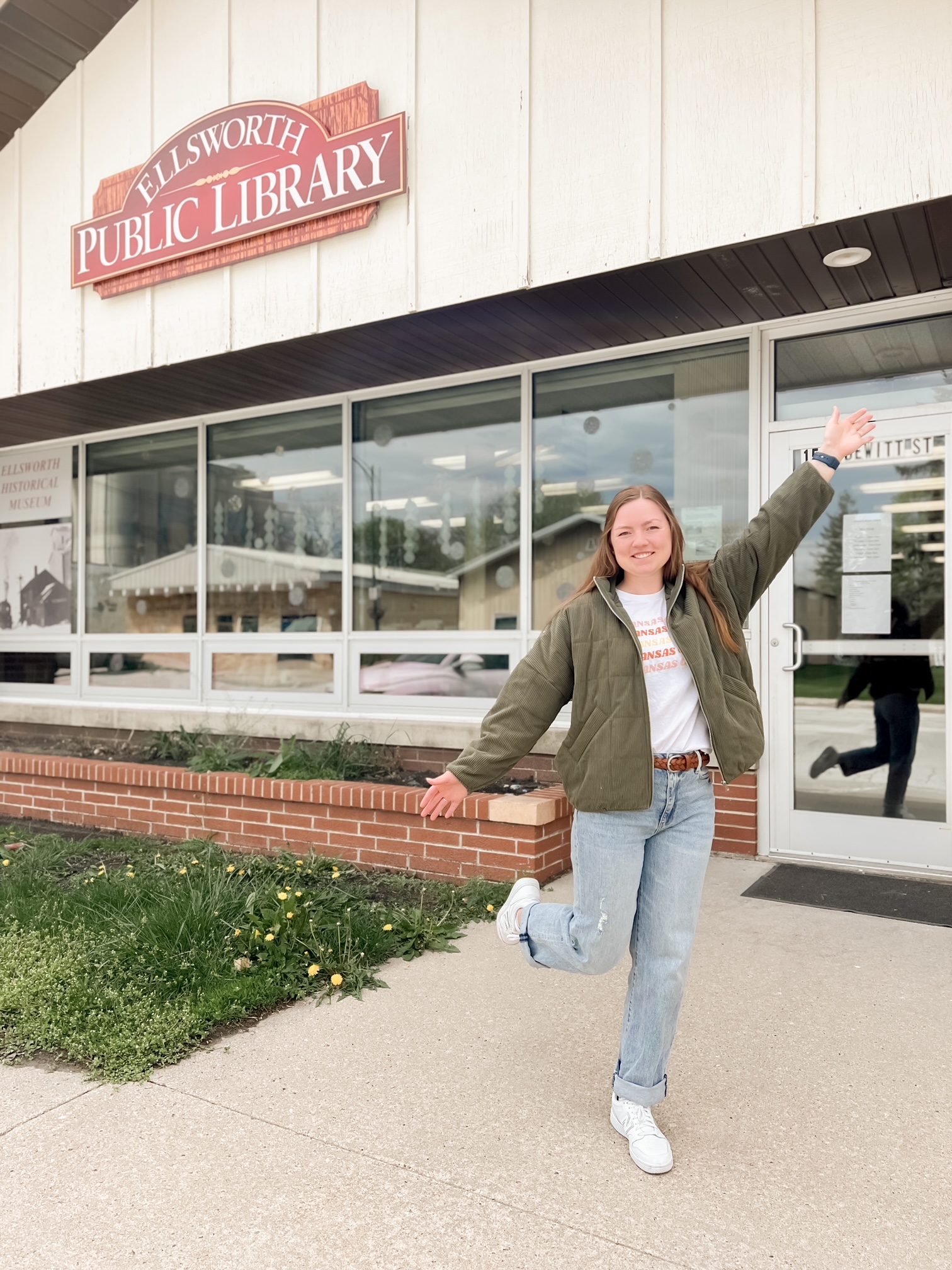 Karlie posing outside the building with the Ellsworth Public Library sign behind her